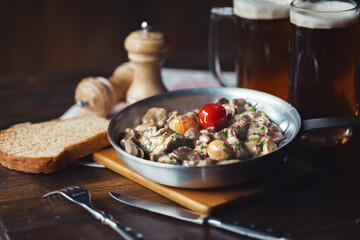 Stewed chicken offal in sour cream with mushrooms, tomatoes, herbs and eggs in a skillet. Hearty...