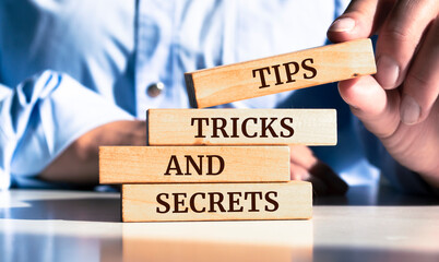 Close up on businessman holding a wooden block with "TIPS, TRICKS AND SECRETS" message