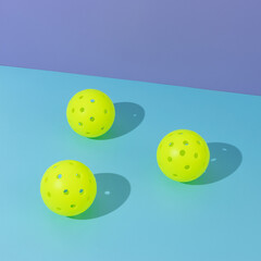 Three pickle ball balls on colorful blue and lavender background, square