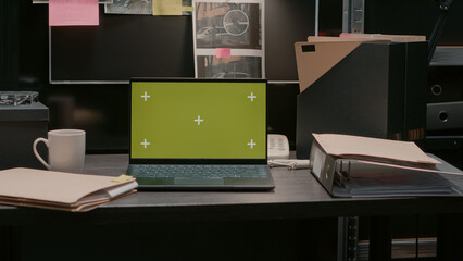 Greenscreen display on portable laptop in incident room, isolated chroma key template. Wireless computer placed on desk showing blank copyspace mockup screen, evidence board map.