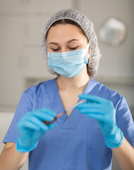 Female nurse in mask holding syringe for injection in hospital