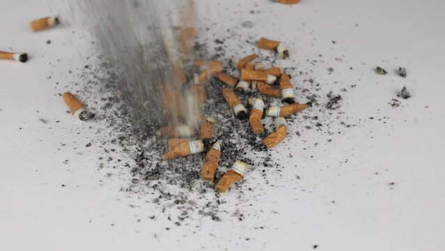 Cigarettes and ashes, many smoked cigarettes scattered on a white cloth. A strong passion for smoking. Harmful to health. Smoking can be harmful to your health. It's a pity for the environment.