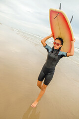 Fototapeta na wymiar Teenage girl with surfboard over head walking on the beach
