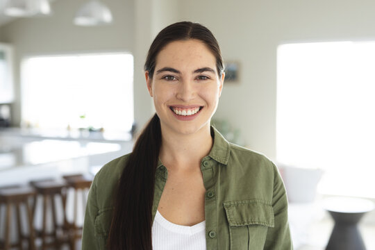 Fototapeta Portrait of smiling caucasian beautiful young woman dressed in jacket standing at home, copy space