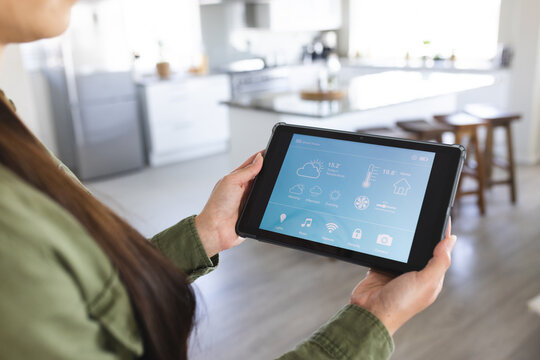 Midsection of caucasian young woman controlling smart home over digital tablet, copy space