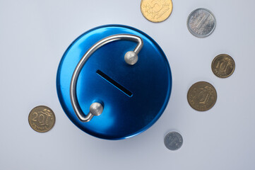Flatlay closeup of a blue metallic piggy bank. Obsolete Finnish markka coins.