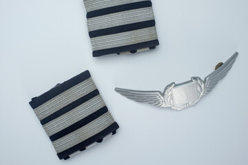 Flatlay closeup of first officer epaulettes and a aviator badge.