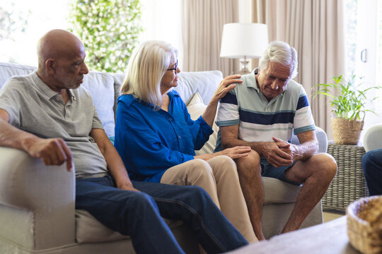 Group of diverse senior friends sitting in living room, talking in group therapy session