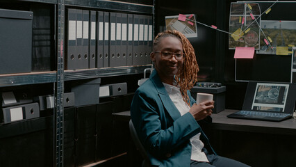 African american woman working in police archive space, preparing to look at physical evidence and...