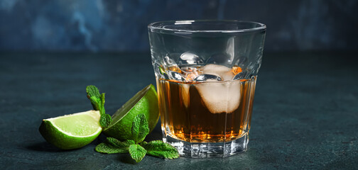 Glass of rum with ice, mint and lime on dark table