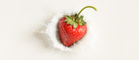 Fresh strawberry falling into milk, top view