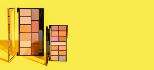 Set of professional makeup cosmetics on yellow background with space for text