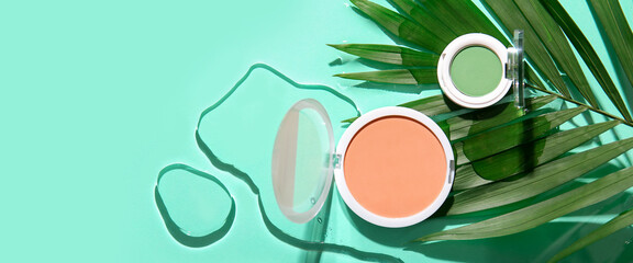 Professional makeup cosmetics with tropical leaf on turquoise background with space for text