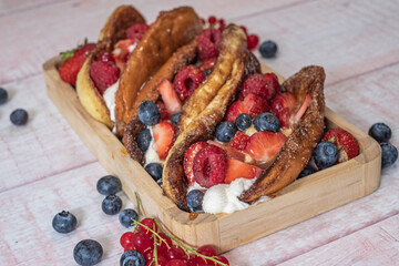 Fresh brown sweet hotdogs with cream cheese and fresh berries - blueberries, strawberries, raspberries and currants. 