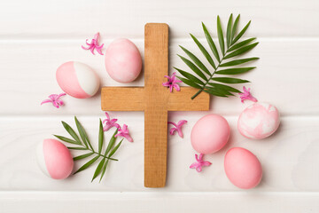 Obraz na płótnie Canvas Pink Easter eggs with cross and leaves on wooden background, top view