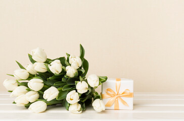 White tulip bouquet with gift box on table