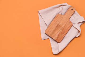 Wooden cutting board and napkin on color background
