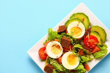Plate of delicious salad with boiled eggs and salmon on blue background