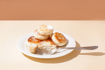 Plate with delicious cottage cheese pancakes on color background