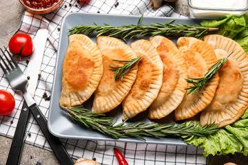 Plate with tasty meat empanadas with rosemary on table, closeup