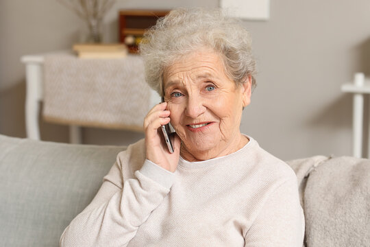 Senior Woman Talking By Mobile Phone On Sofa At Home, Closeup