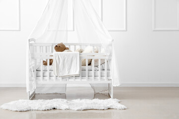 Fototapeta na wymiar Baby crib with toy bear in light bedroom
