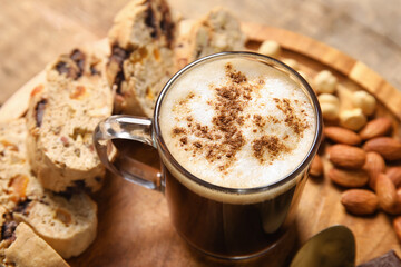 Board with delicious biscotti cookies, nuts and cup of coffee on wooden background