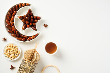 Ramadan Kareem concept. Crescent and star plate with dried dates, arabic lantern, nuts, rosary...