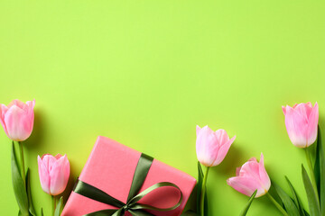 Flat lay composition with tulips and gift box on green background. Happy Mother Day concept