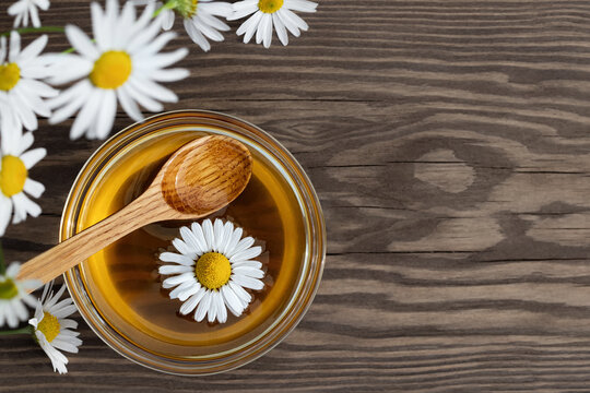 Chamomile syrup in a small bowl and in a jar in the patio on a wooden table