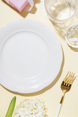 Clean plate, fork and glass on beige background