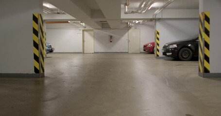 Underground car parking garage with dirty floor in season. Black rolls of dirt from the wheels. Black and yellow corner stripes. Sections for cars near the wall. - Powered by Adobe