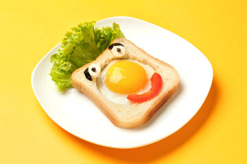 Plate with funny toast on yellow background