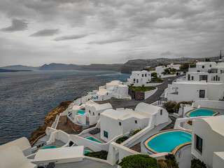 View of Fira town in Santorini island in Greece. Landscape with traditional white houses with swimming pools on a cloudy day