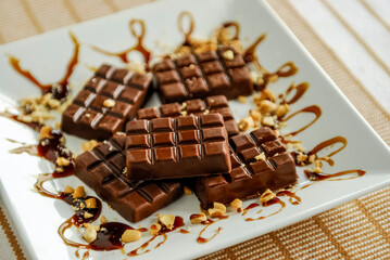 Homemade Brazilian chocolate bar on a white plate with cashew nut pieces.