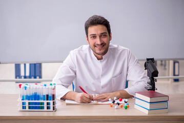 Young male chemist sitting in the classroom