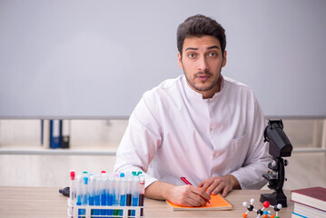 Young male chemist sitting in the classroom