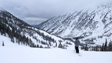 Snow covered Wasatch mountains with lone skier overlooking the valley 
