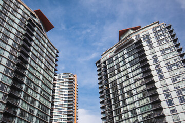 Modern highrise building or tall residential towers with blue sky. Group of tall glass buildings. Empty homes tax, speculation tax or gentrification concept. Vancouver, BC, Canada. Selective focus.