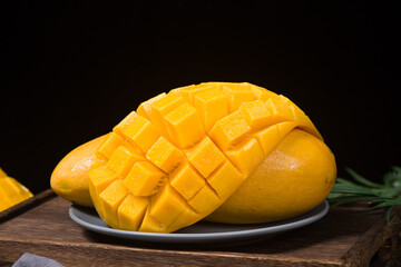 Yellow mango with slice on wooden table.