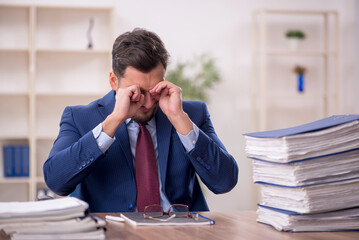 Young male employee and too much work in the office