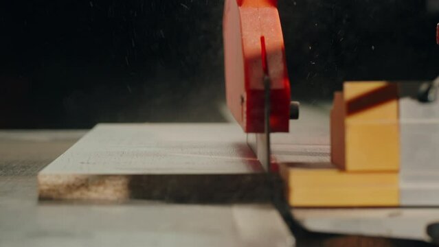Close-up of carpenter cutting a wooden plank, circular saw on wooden factory, furniture production, handmade craft table.
