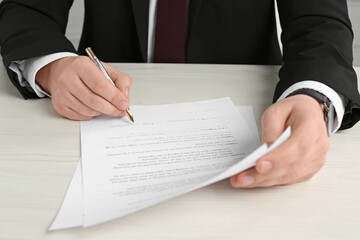 Notary signing document at wooden table, closeup