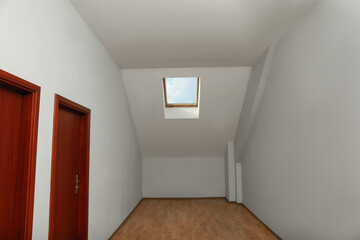 Light spacious attic room with roof window on slanted ceiling