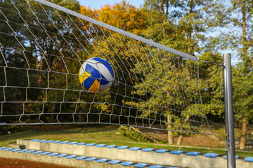 Ball hitting into volleyball net on court outdoors