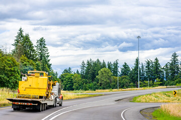 Heavy duty big rig semi truck tractor transporting oversized cargo on step down semi trailer...