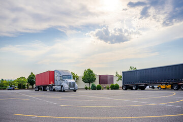 Heavy duty gray big rig semi truck with loaded container on the flat bed semi trailer standing on...