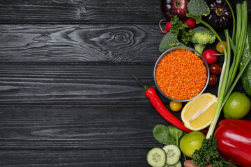 Different vegetables on black wooden table, flat lay with space for text. Vegan diet