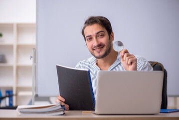 Young male teacher sitting in the classroom