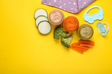 Flat lay composition with glass jars of healthy baby food and ingredients on yellow background. Space for text